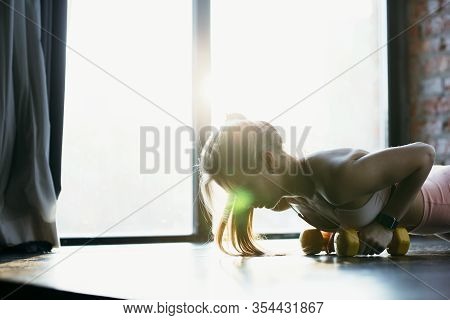 Close-up Of A Girl Training With Yellow Dumbbells In The Gym. Workout In Spotswear Near The Window.