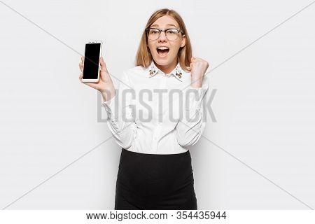 Image Of A Young Pregnant Businesswoman Wearing Glasses, Shocked Girl Shows A Blank Smartphone Scree