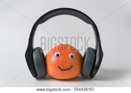 Food With Funny Faces With Headphones On White Background. Orange With Eyes And Smile.