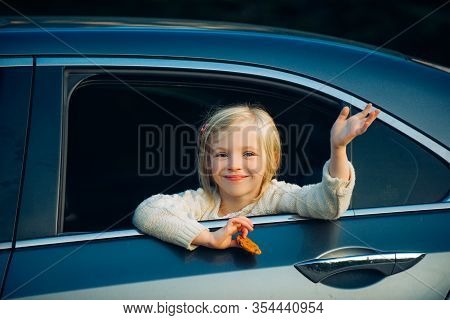 Cute Little Girl Traveling In The Car And Observing Nature From Open Window. Little Girl Waving Hand