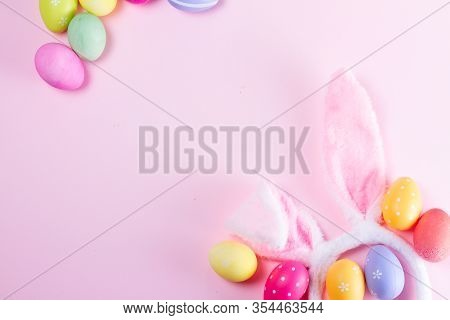 Easter Rabbit Flaffy Ears And Colored Easter Colored Eggs Frame On Pink Background, Flat Lay With Co