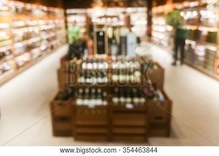 Blurred Wine Section Of Retailer With Bottles On Shelf Display Rack
