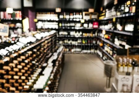 Blurred Wine Section Of Retailer With Bottles On Shelf Display Rack