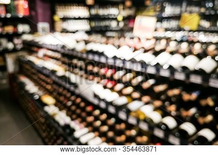 Blurred Wine Section Of Retailer With Bottles On Shelf Display Rack