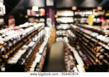 Blurred Wine Section Of Retailer With Bottles On Shelf Display Rack