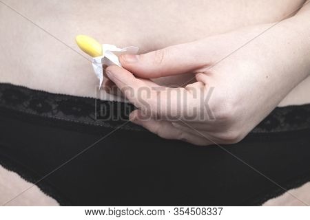 Vaginal Or Rectal Candle In The Hands Of A Woman Against The Background Of The Abdomen And Underwear