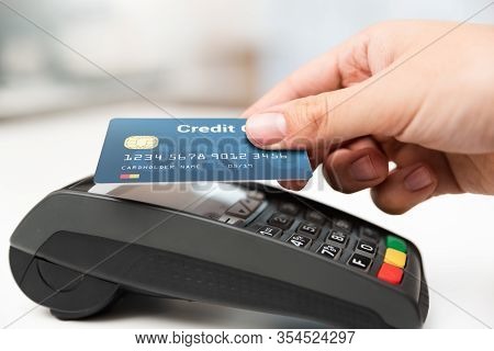 Man Using Credit Card In Shop. Cashless Payment With Pos Terminal
