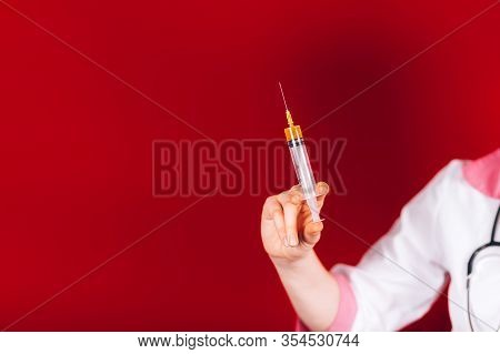 Young Girl Doctor Holding Syringe With Blood In His Hand In A White Coat On Red Background