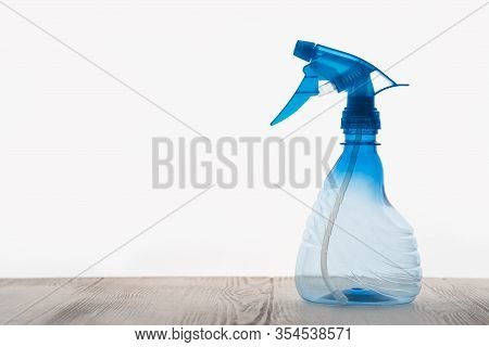 Side View On An Empty Hand-held Fluid Bullet, Plastic Is Transparent Blue, Table Is Wooden With Text