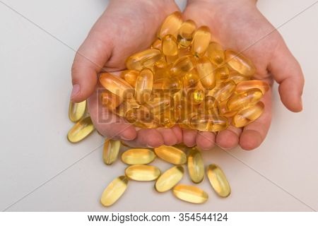 Vitaminen Omega 3 Fish Oil In Capsules In Hand On Beige Background.