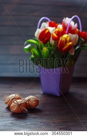 Easter Beige Eggs Decorate With Rope And Bouquet Of Different Color Tulps On Brown Wooden Background