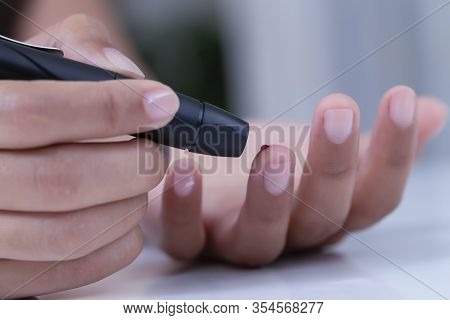 Female Using Lancelet On Finger, Diabetic Checking Blood Sugar Levels.