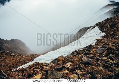 Snow On Abyss Edge Inside Cloud. Deep Abysm In Haze. View To Down To Chasm Within Clouds. Atmospheri
