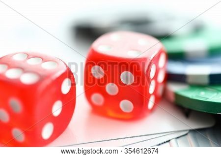 Close-up View Of Red Glass Dice Cubes On Playing Cards. Colourful Casino Chips On Table. Risk And Lu