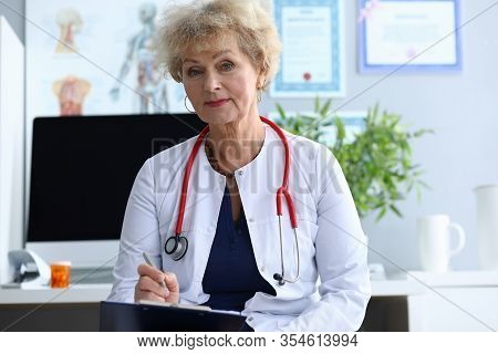Portrait Of Smiling Lady Looking At Camera With Gladness. Cheerful Elderly Woman Writing Information