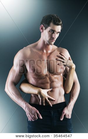 Sexy muscular naked man and female hands holding his chest