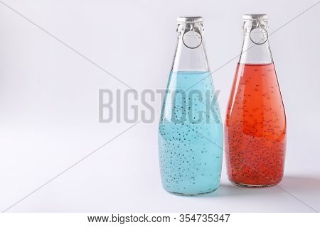 Blue And Red Drinks With Basil Seeds Or Falooda Seeds Or Tukmaria In Bottles On White Background, Co
