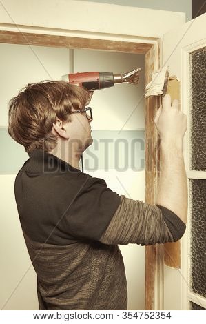 Man At Home Removing Havy Layer Of Old Paint From Door