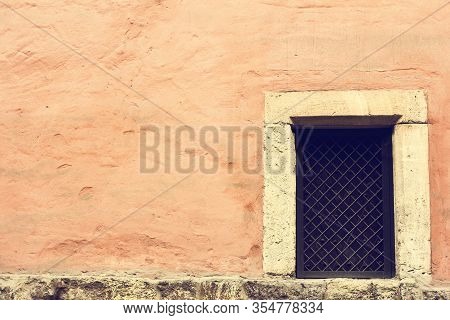 Aged Pink Wall With Window With Bars. Closed Window In A Dismissed Warehouse, Frosted Pane And A Gra