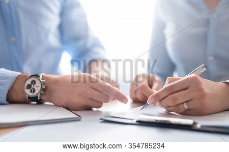 Business People Negotiating A Contract. Human Hands Working With Documents At Desk And Signing Contr