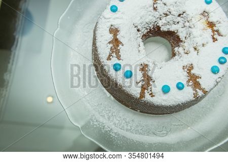 A Festive Round Cake Sprinkled With Powdered Sugar Lies.