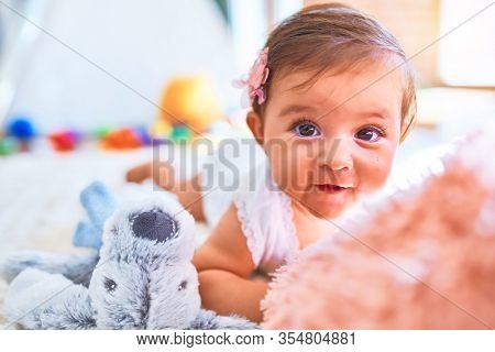 Beautiful infant happy at kindergarten around colorful toys lying on blacket