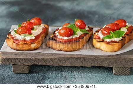 Italian Bruschettas With Mozzarella, Riccotta, Baked Tomatoes And Basil