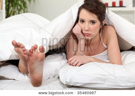 Infeliz mulher deitada ao lado de pés do namorado