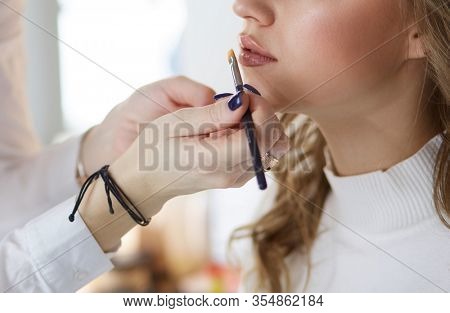 make up artist doing professional make up of young woman