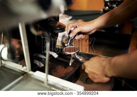Barista Holding Coffee Tamper And Tamping Arabica Grounds In Espresso Double Spout Portafilter Befor
