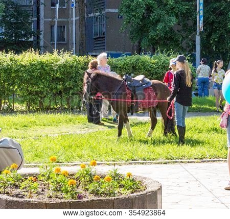 Udomlya, Russia - June 1, 2016: Ponies, Women And Children On International Childrens Day.