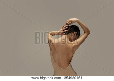 Graceful Classic Ballerina Dancing, Posing Isolated On Pastel Brown Studio Background. Females Back 