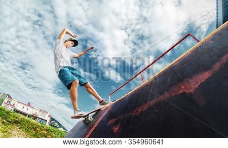 Portrait Of A Young Skateboarder Doing A Trick On His Skateboard On A Halfpipe Ramp In A Skate Park 