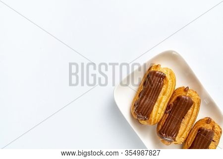 Copy Space. Fragment Plate Custard Cakes With Chocolate Icing And Coffee On A White Background.