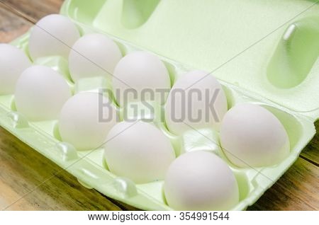 White Eggs In Green Plastic Packaging On A Wooden Background Close Up