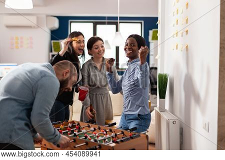 Happy Woman Celebrating Foosball Game Win At Office Party After Hours, Enjoying Alcoholic Drinks Wit