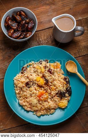 A Large Dish Of Couscous On A Wooden Table Next To Dates Nuts And A Jug Of Fruit Broth. Vertical Pho