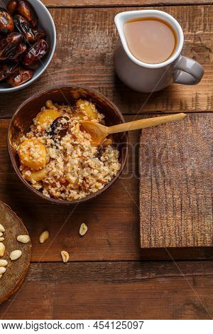 A Plate Of Couscous With Saffron And Nuts On A Wooden Table Nearby And A Jug Of Fruit Broth. Vertica