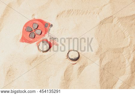 Red Gaming Gamepad Buried In The Sand. Buttons And Controls Stick Out Of The Sand. Gamepad In The Sa