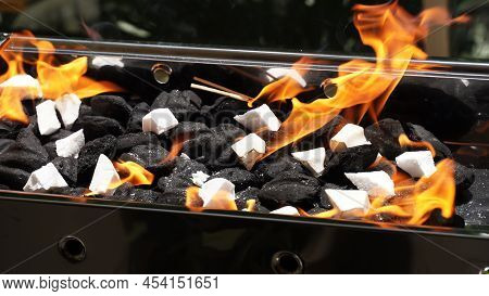 Empty Barbecue Flaming Grill Close Up With Bright Flames And White Firelighters Burning