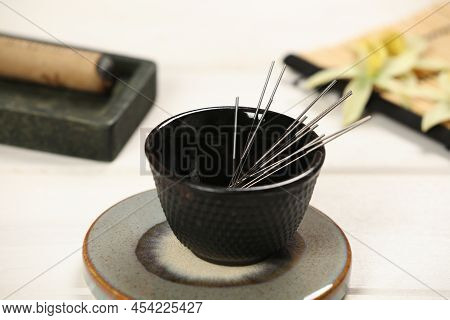 Bowl With Acupuncture Needles On White Wooden Table, Closeup