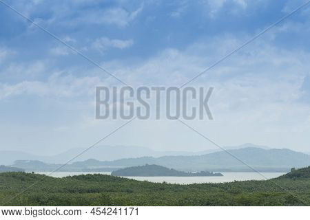 Landscape View Of Hills Covered With Trees. Surrounded By A Large Prasae Reservoir. Under Blue Sky A