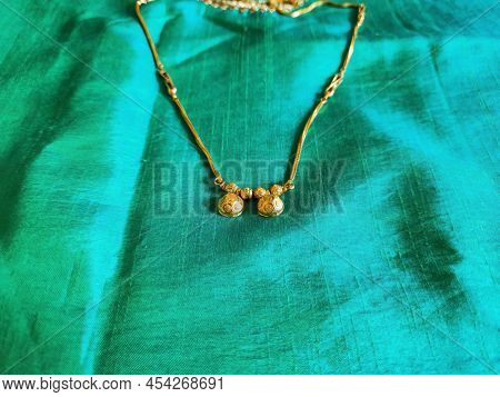 Stock Photo Of Beautiful Fancy Golden Mangalsutra With Golden Chain On Sea Green Nursery Color On Ba