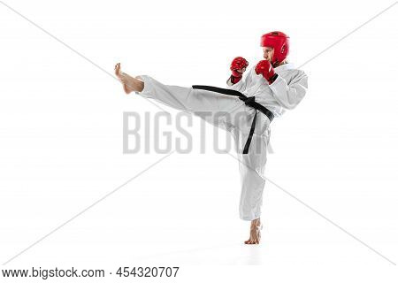 Portrait Of Young Sportive Man Wearing White Dobok, Helmet And Gloves Practicing Isolated Over White