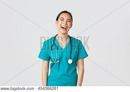 Covid-19, Healthcare Workers, Pandemic Concept. Carefree Beautiful Female Asian Nurse In Scrubs, Int