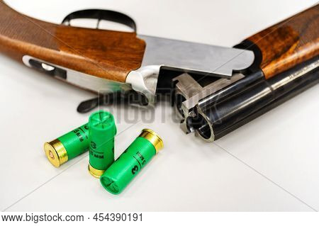 Fragment Of A Hunting Shotgun With Ammunition. Plastic Cartridges And Firearms Lies On A White Backg