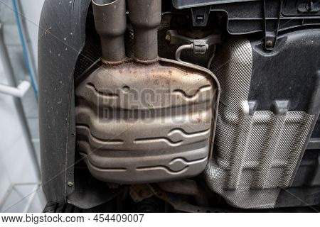Close-up Detail Bottom View Of Car Part Metal Exhaust Muffler Pipe With Rusty Stains. Lifted Vehicle