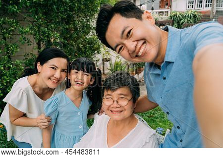Group Of Multi-generational Asian Family Taking A Selfie Photo Together In Backyard Garden And Smili