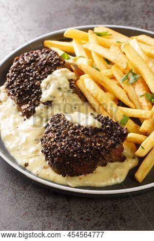 Homemade Steak Au Poivre With Pepper Sauce Served With French Fries Close-up In A Plate On The Table