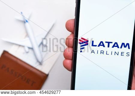 Latam Airlines Logo On The Mobile Phone Screen With A Plane, Passport And Boarding Pass On The Backg